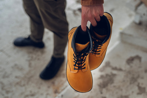 Man holding Ahinsa shoes winter barefoot boots with a wide toe box