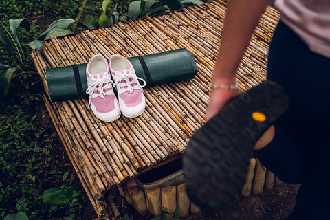 stretching woman in trail shoes, road-running footwear by Ahinsa shoes is lying in background