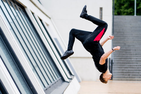 man in barefoot shoes is performing a backflip